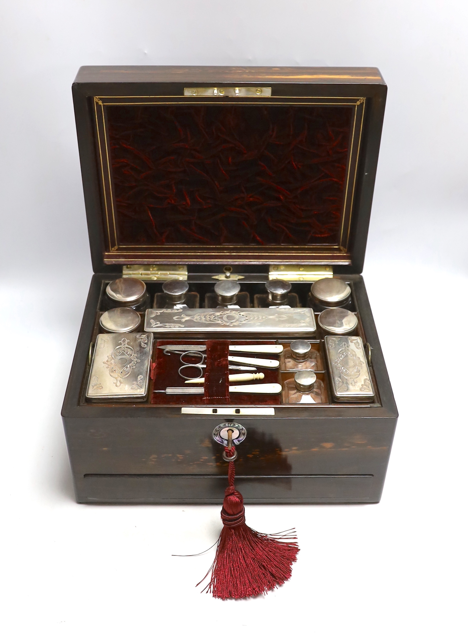 A Victorian coromandel wood toilet box with plated fittings and Mother of Pearl inlay to lid, fitted internal compartments containing glass bottles with plated lids and other accessories, and jewellery drawer underneath